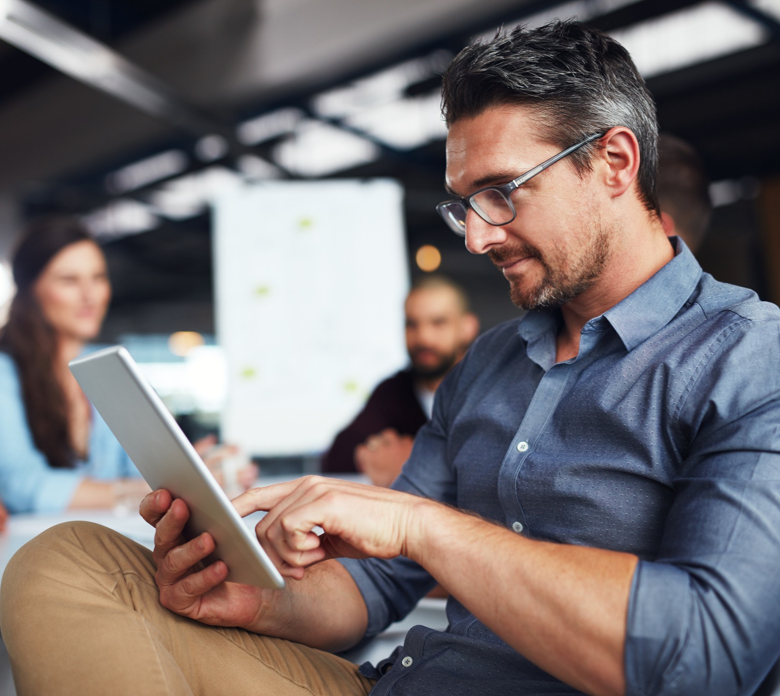 Millenial man working on tablet with team