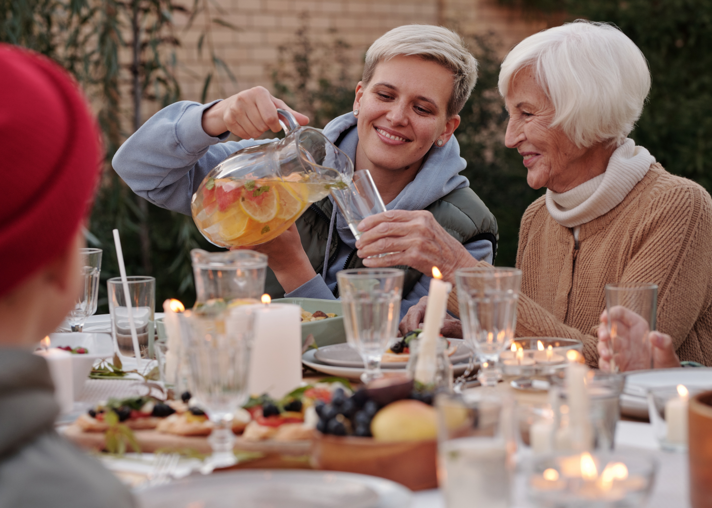 Person pouring a glass of water for an older woman.