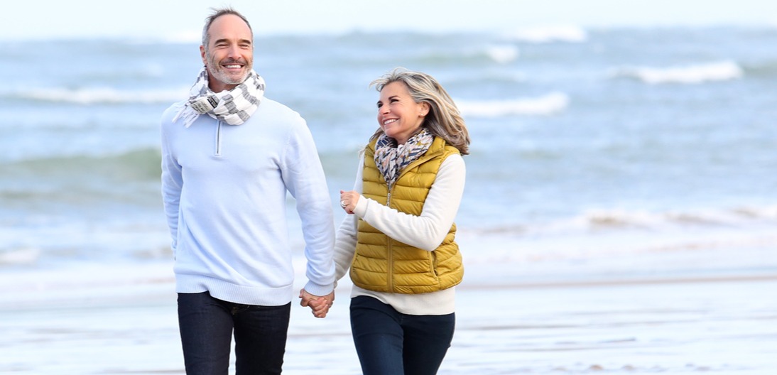 An elderly couple strolling around the beach.