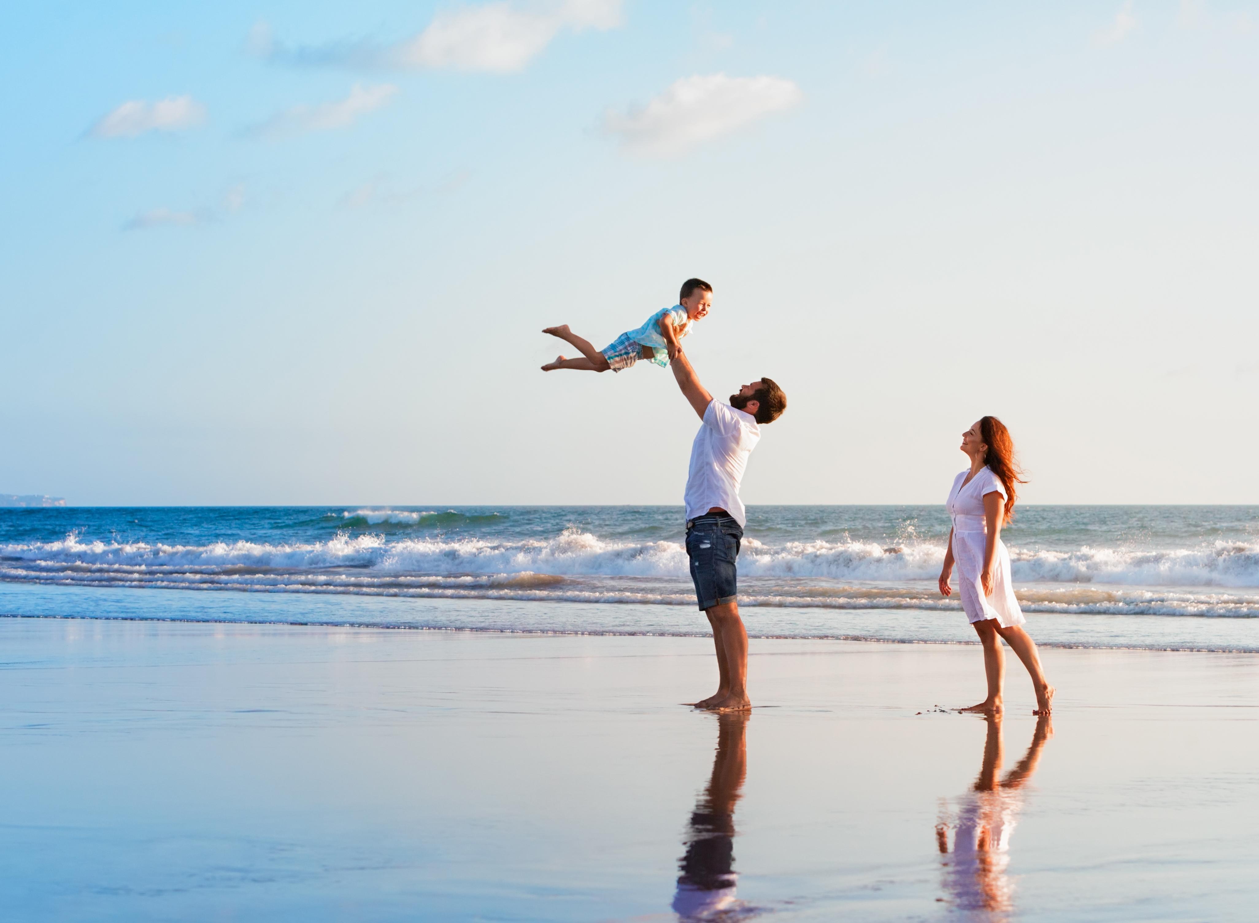 Father holding up son on a beach