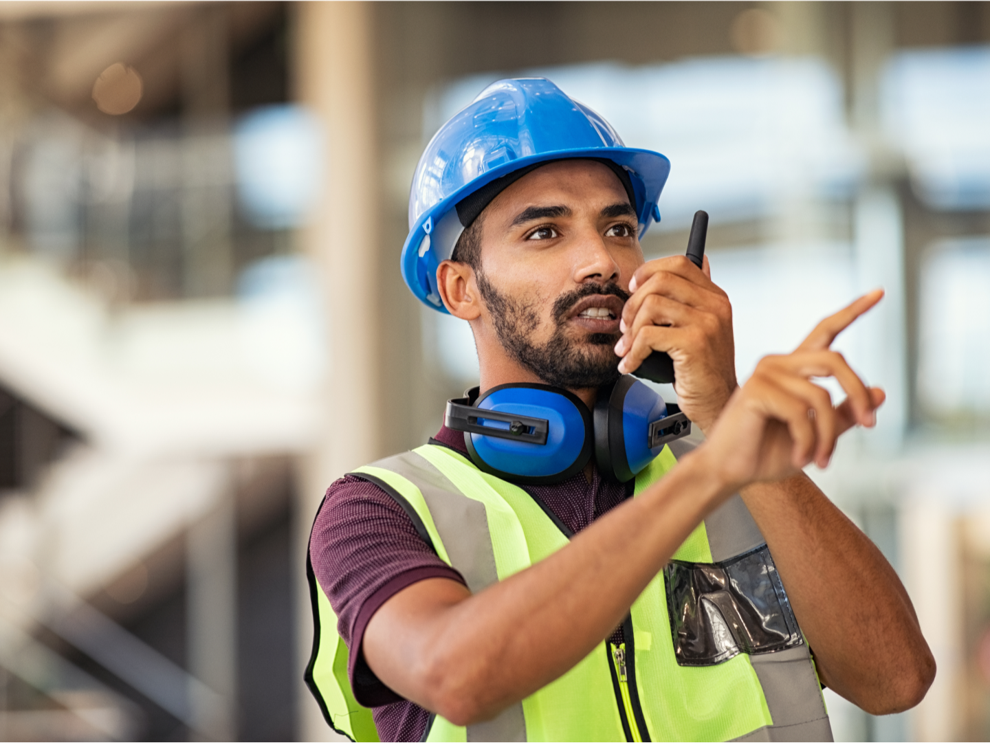 worker in a hard hat and safety vest talking on a walkie talkie<br/>