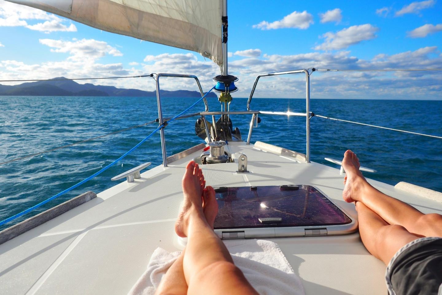 First person image of two people sitting on a boat in a body of water with mountains in the background