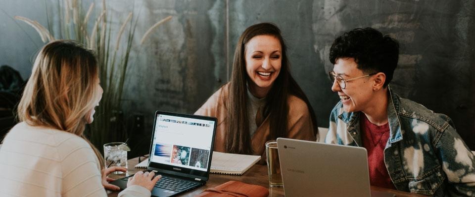Group of adults laughing while working on laptops