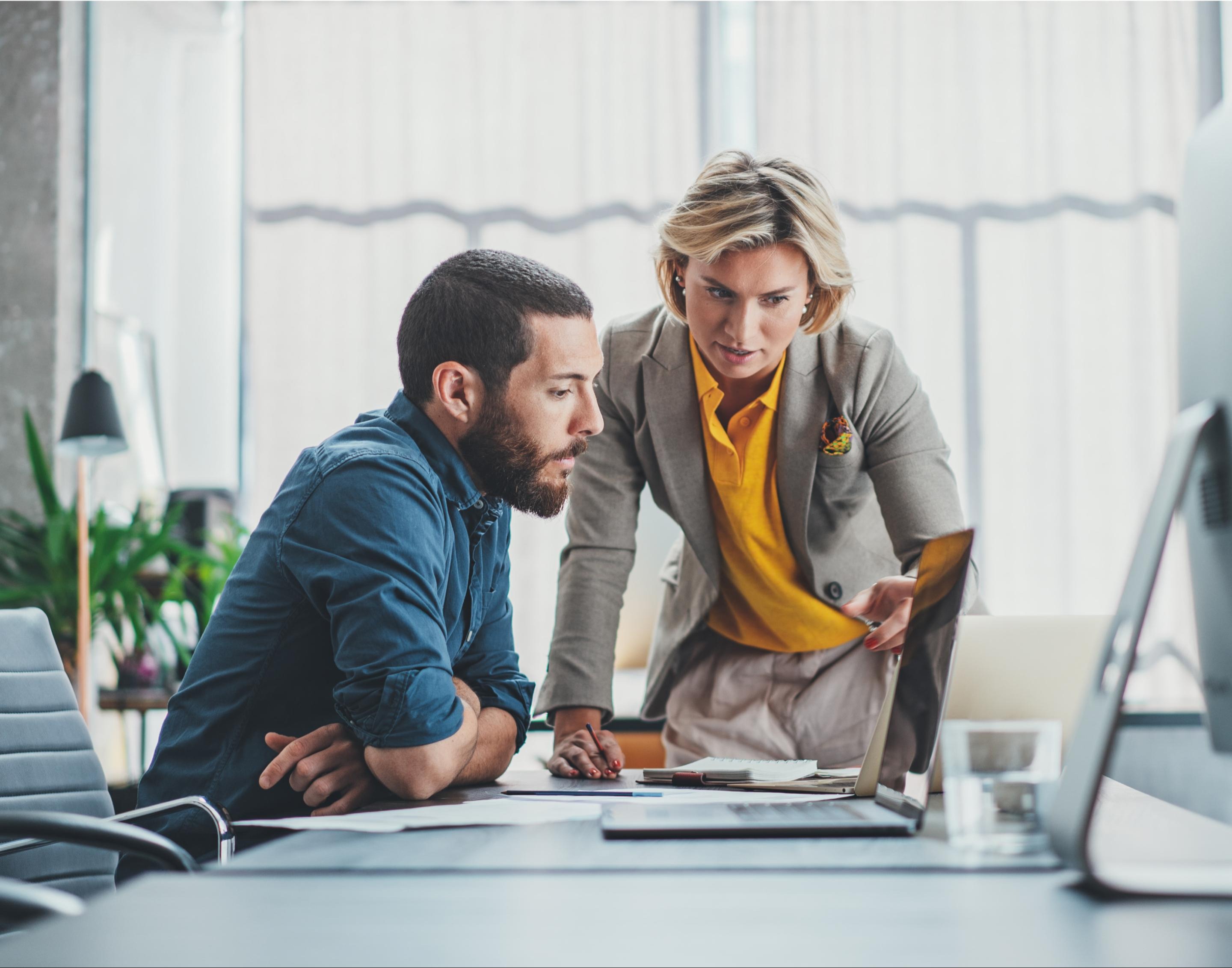 Two people looking at a laptop and having a discussion
