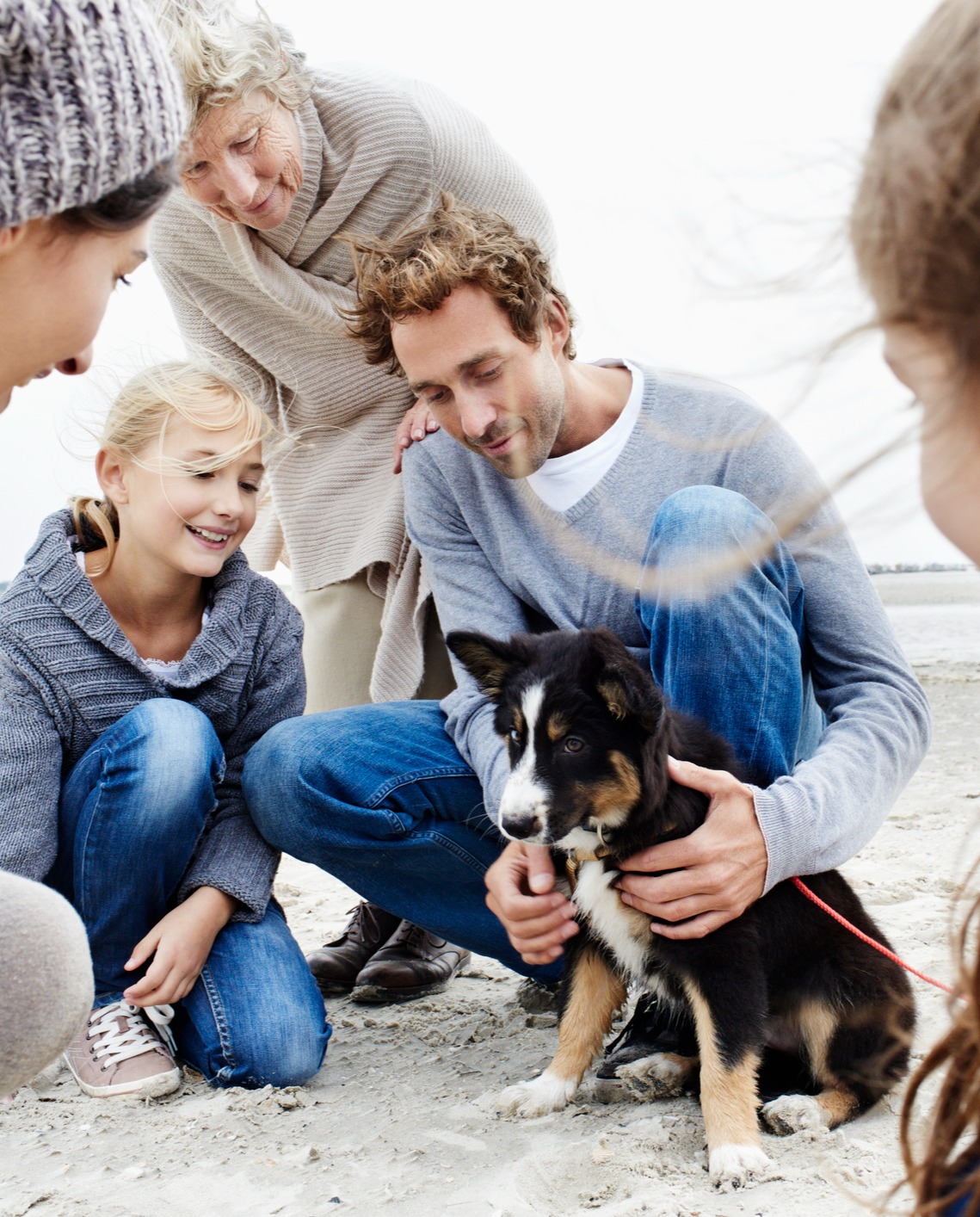 multi-generational family on a beach with a puppy