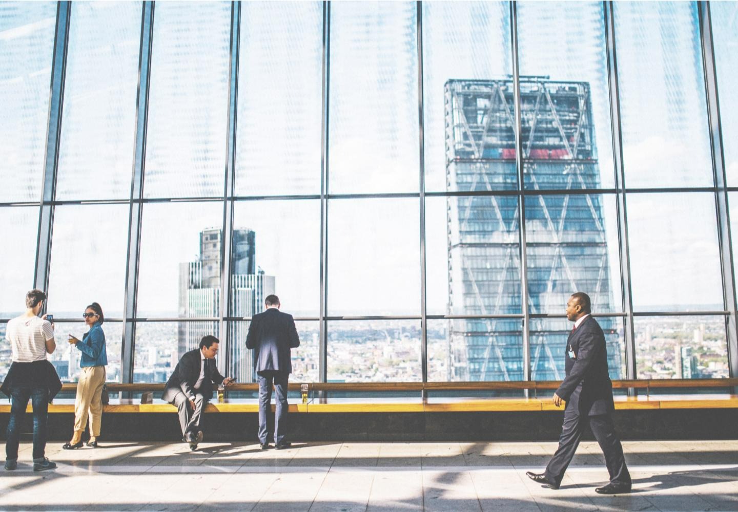 people in a skyscraper next to large windows that look out on the city