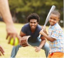 A child and a young person play baseball with a third person offscreen.