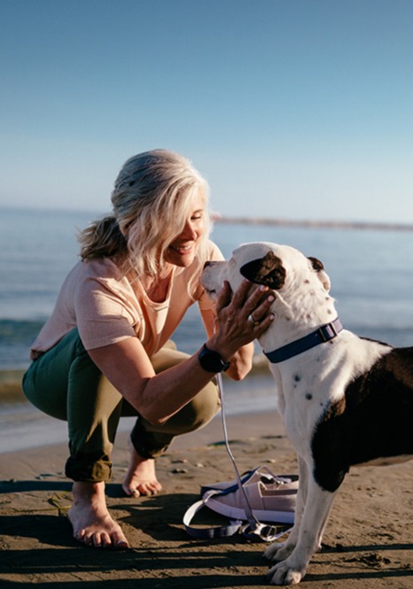 Woman petting dog on a beach
