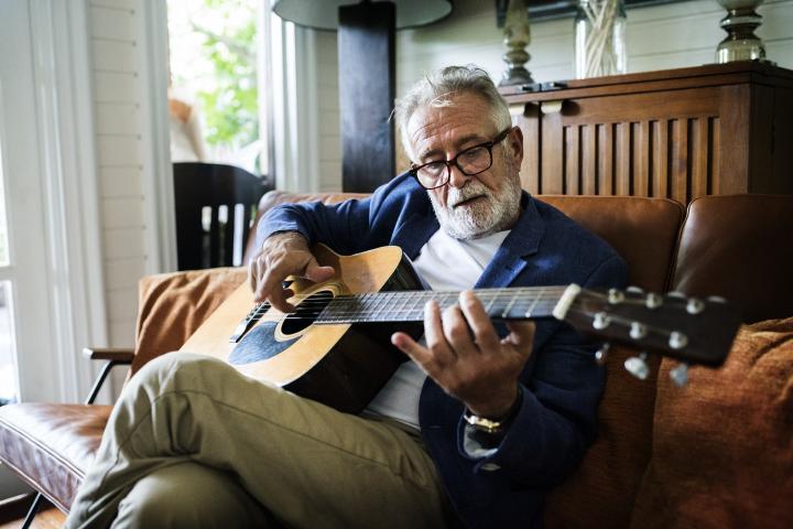 man playing acoustic guitar on a couch