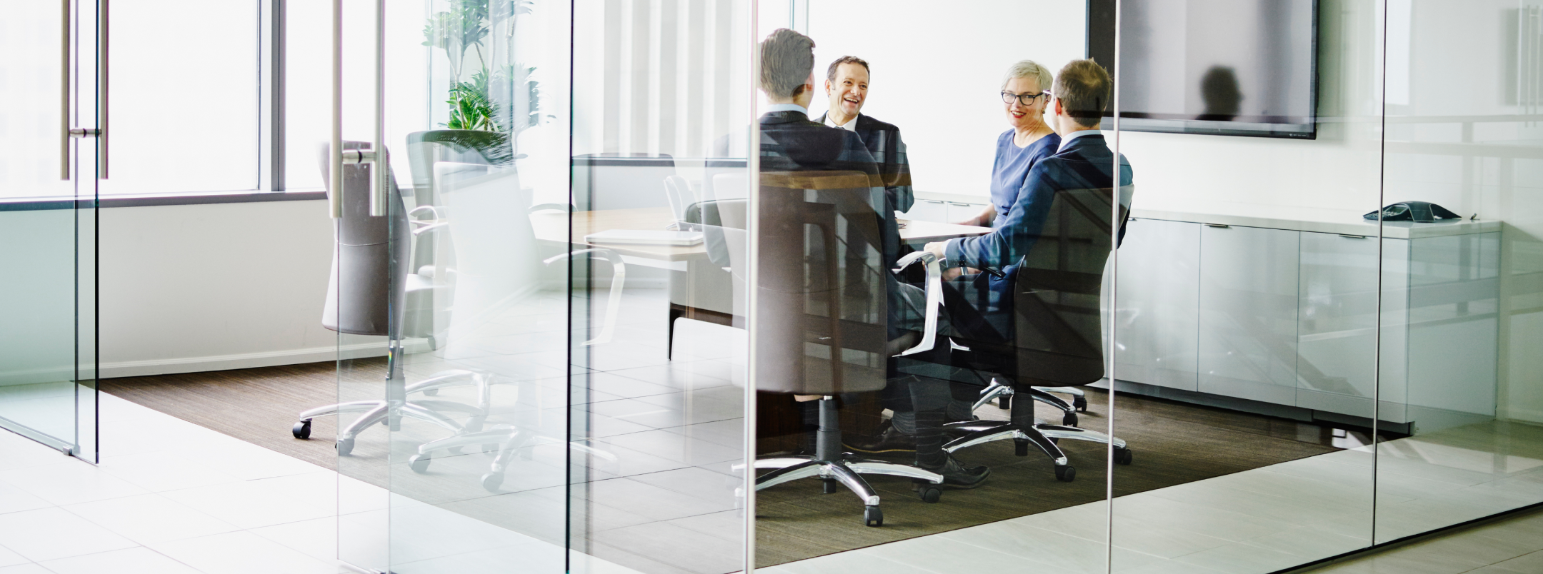 Professionals meeting in an office, surrounded by windows.