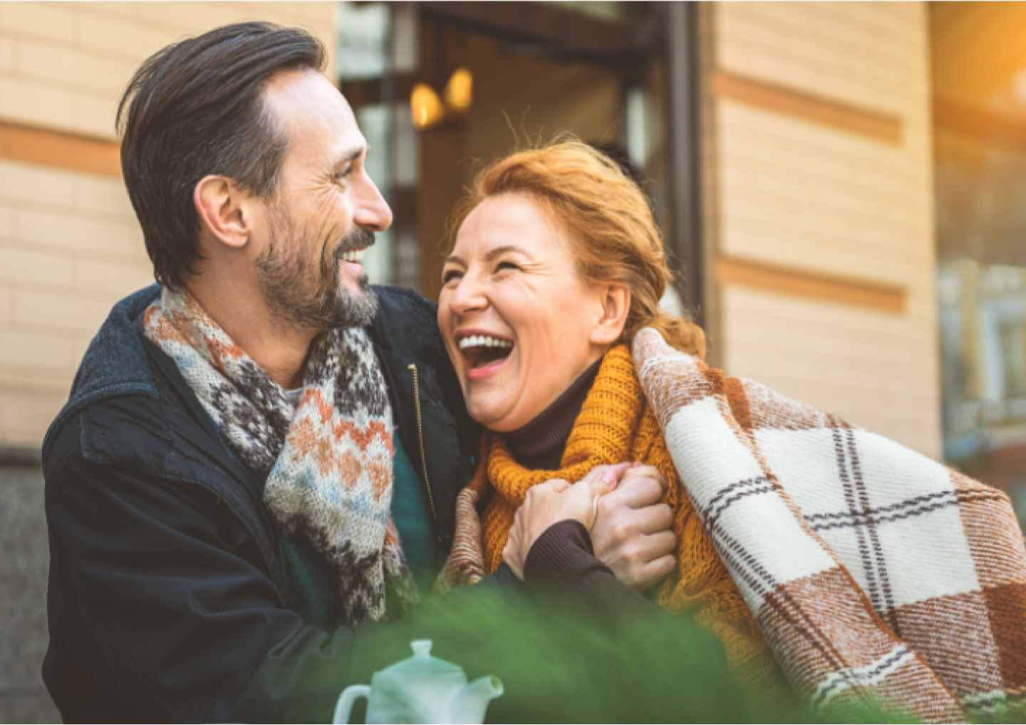 Two people in blankets laughing outside