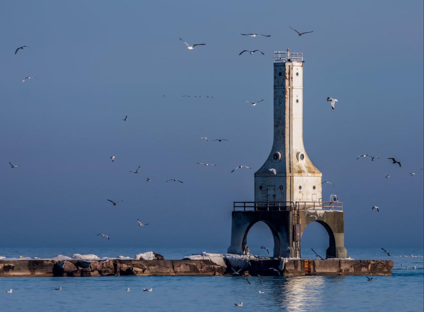 Photo of a lighthouse with seagulls flying around