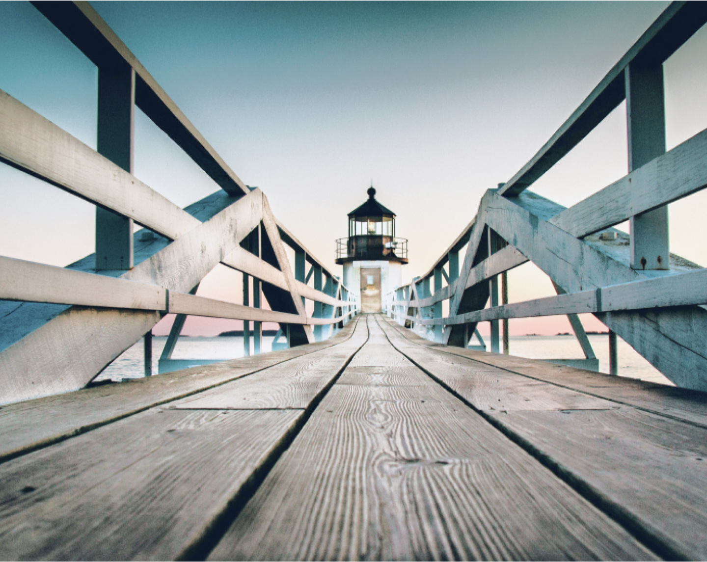 Wooden dock leading to a light house.