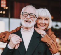 Older Couple Hugging While one Smiles