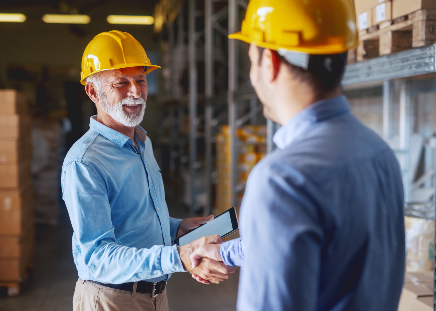 two men in hard hats shaking hands in a warehouse