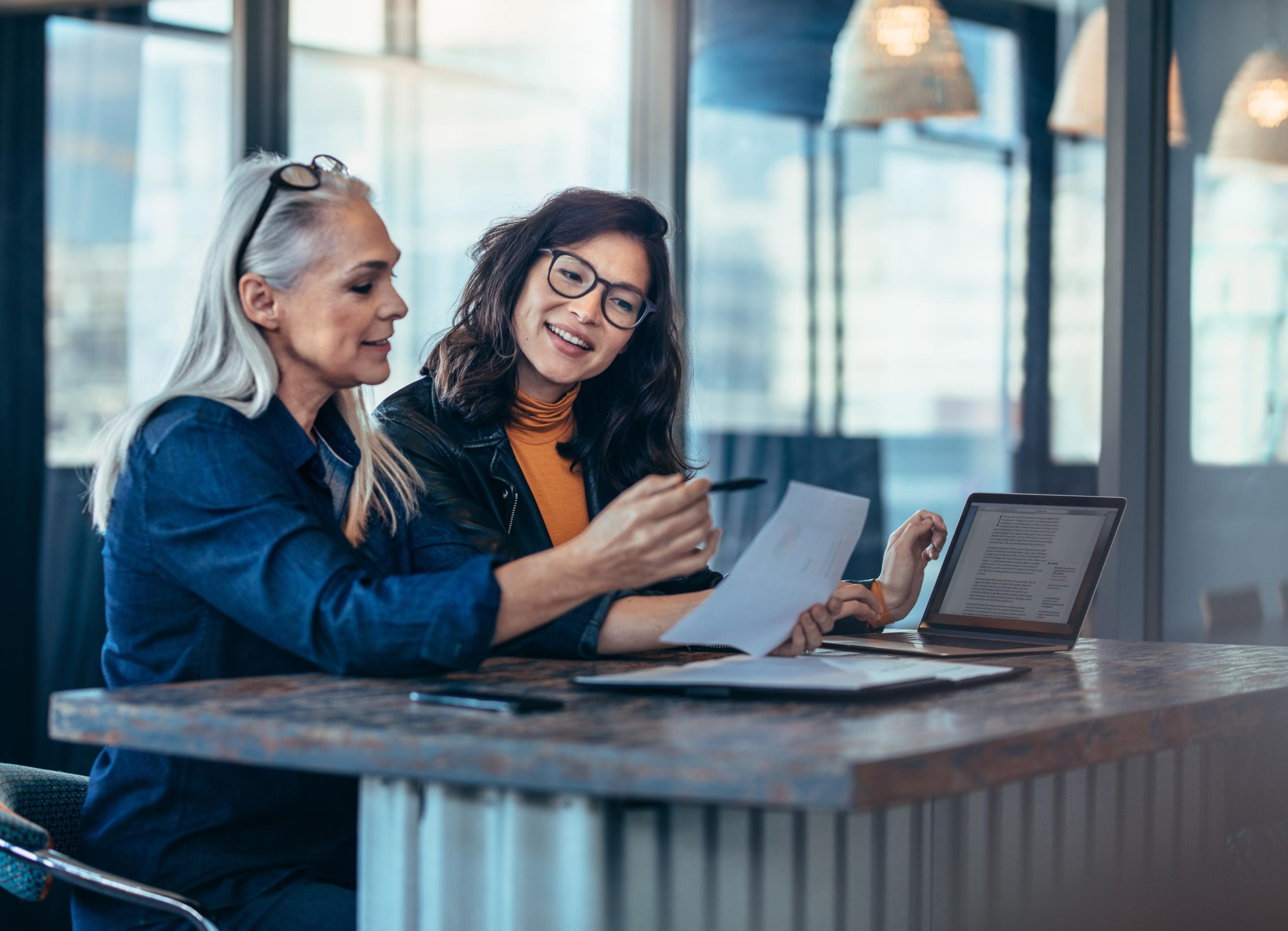 Two women at a desk looking at a paper