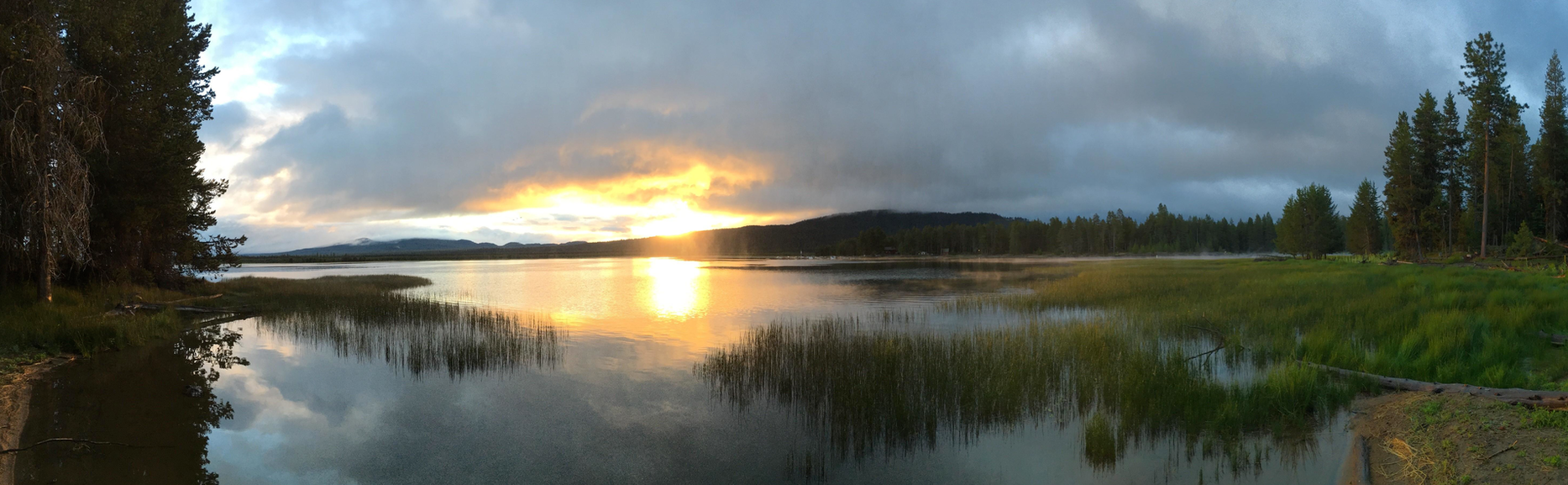 A serene lake in a foresr with a beutiful sunset view