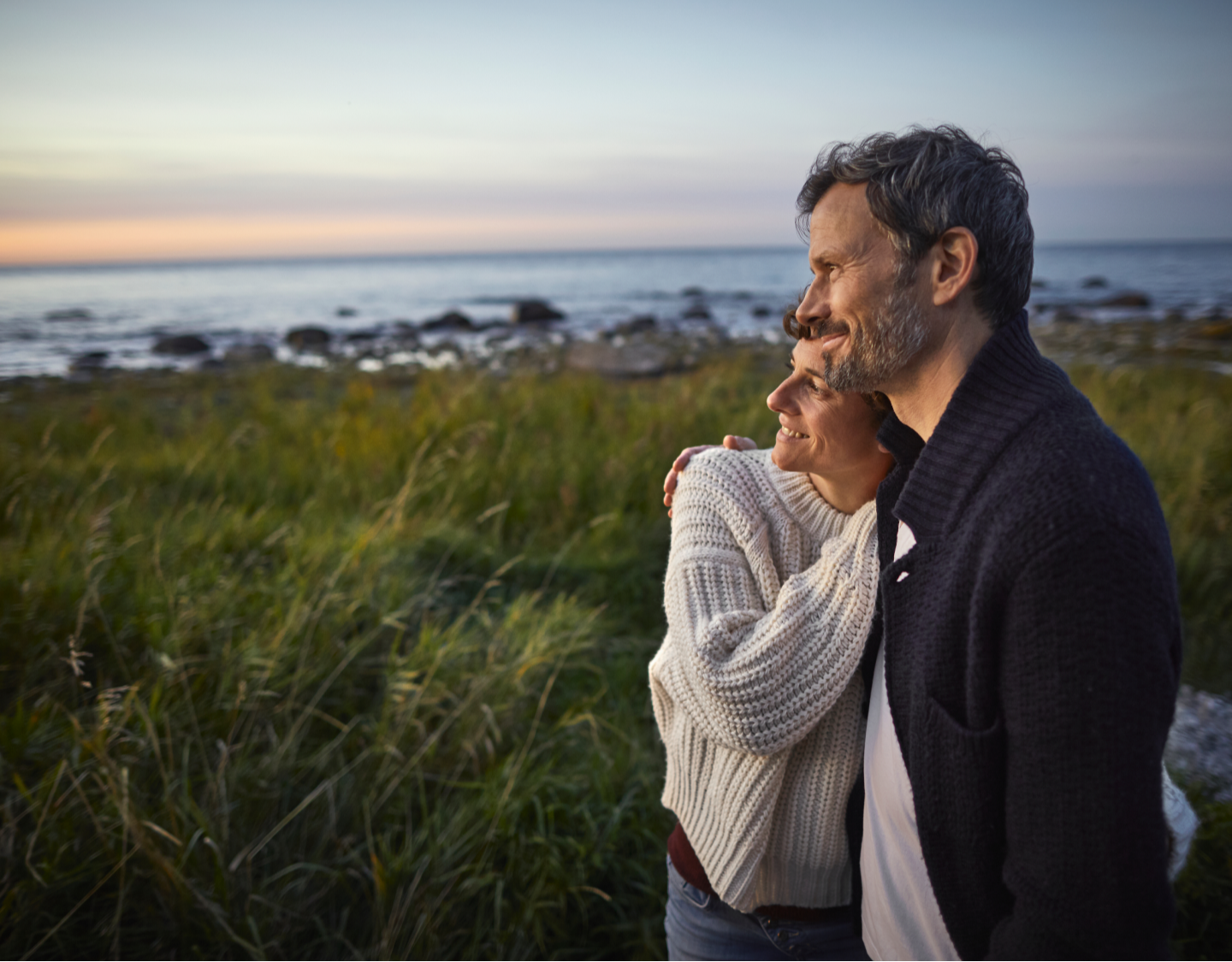 Man and woman at the beach, hugging and looking at view