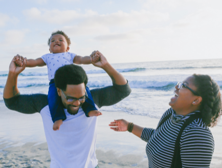 Couple at the beach with young child on fathers shoulders