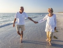 Elderly couple smiling while holding hands at a beach