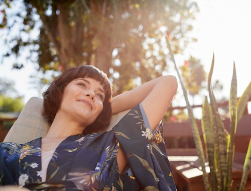 a woman lounging on a chair outside looking relaxed and staring off into the distance