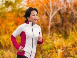 Woman jogging through forest.