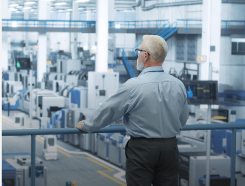 A business owner looking out over the factory floor of his manufacturing company