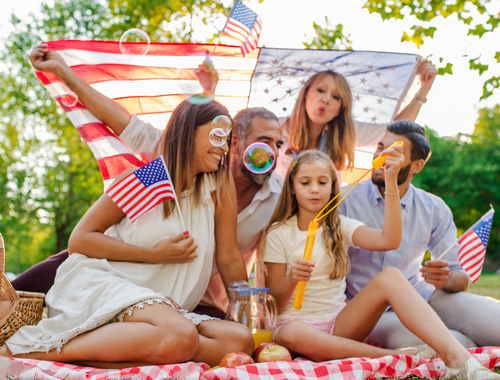 family holding American flags outside on a blanket