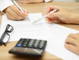 Two people reviewing documents next to a calculator