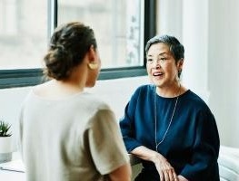 Two people conversing in an office, one away from camera.