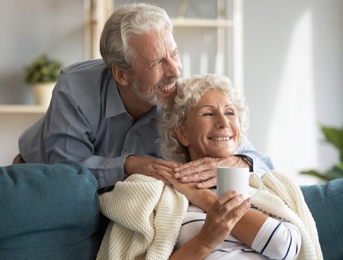 Older gentleman embracing his wife as they reminisce about moving back to Canada after working in the US, feeling happy about managing their 401K in Canada and Roth IRA.