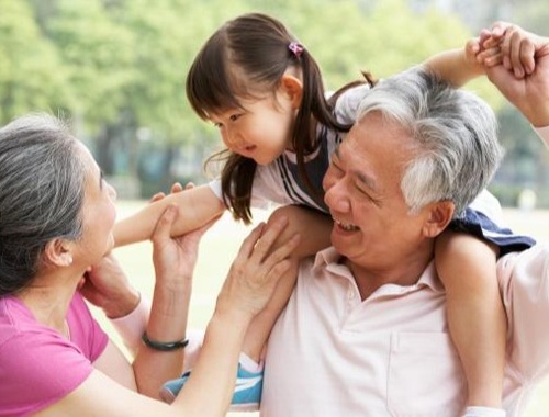 Grandparents giving granddaughter ride on shoulders