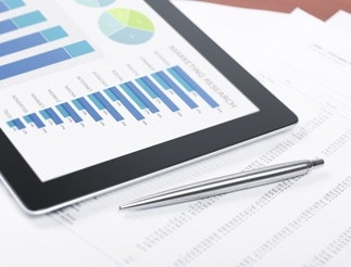 tablet computer and a pen on top of papers with figures