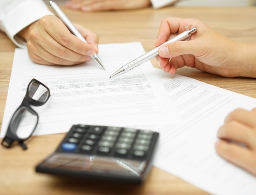 two people point and documents with silver pens