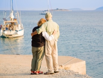 older couple by the water looking out at a moored boat