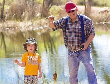 Little boy and his grandfather catching a fish