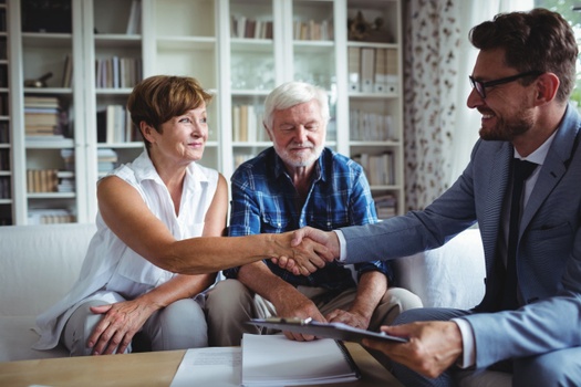 Woman shaking hand with man in a three person meeting